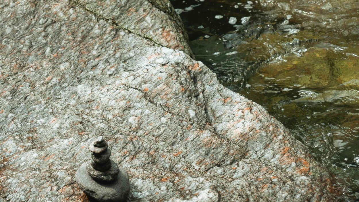 Cascata Stieber: la forza della natura dell’Alto Adige Piccola pila di pietre su roccia accanto a acqua corrente