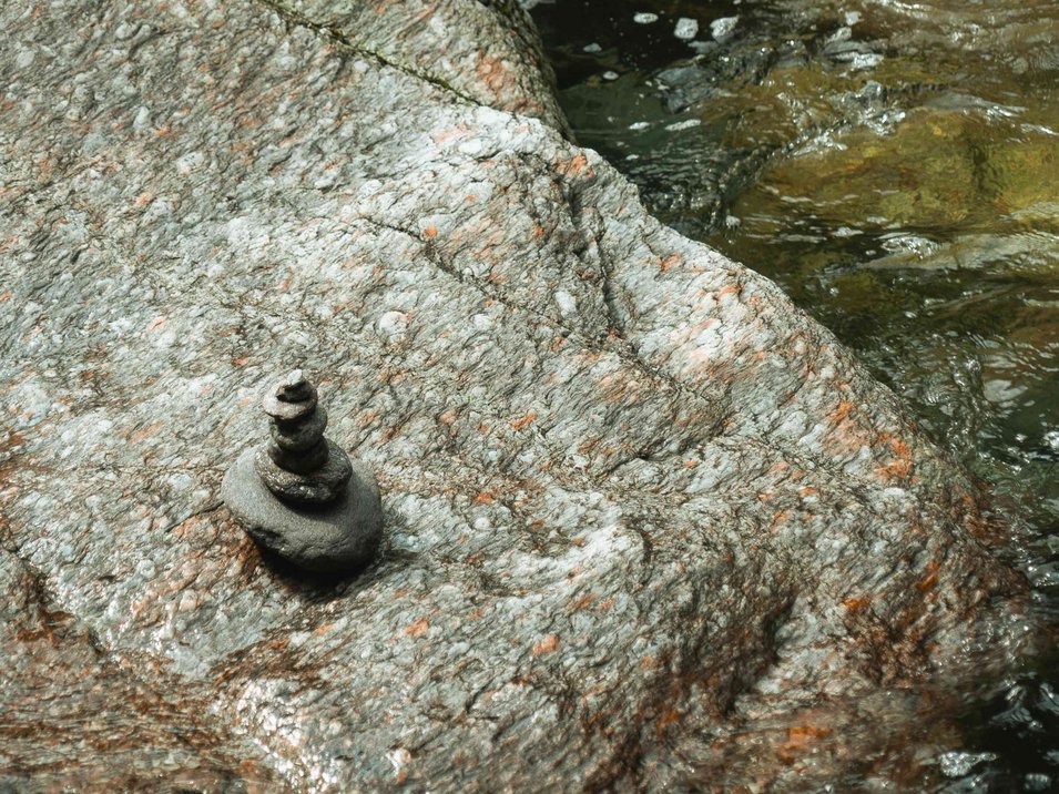 Die eindrucksvollsten Wasserfälle Südtirols Kleine Steinstapel auf Felsen neben fließendem Wasser