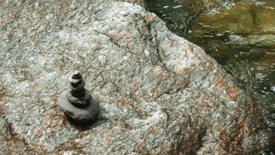 Die eindrucksvollsten Wasserfälle Südtirols Kleine Steinstapel auf Felsen neben fließendem Wasser