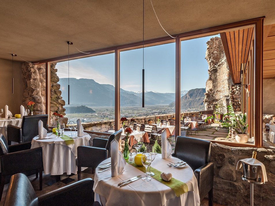 Castel Flavon a Bolzano Ristorante con tavoli, sedie e vista sulle montagne attraverso grandi finestre