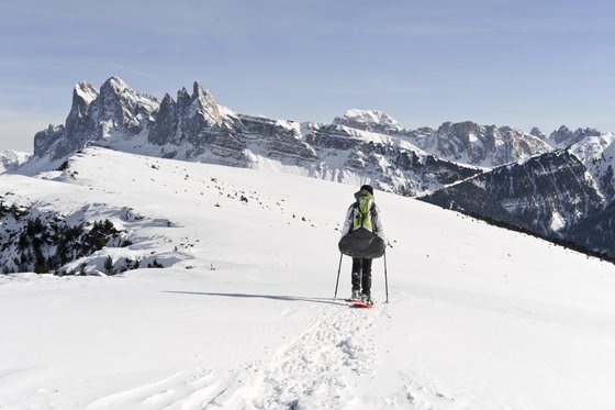 Hotel per escursionisti in Alto Adige Persona con ciaspole cammina in paesaggio montano innevato con montagne sullo sfondo