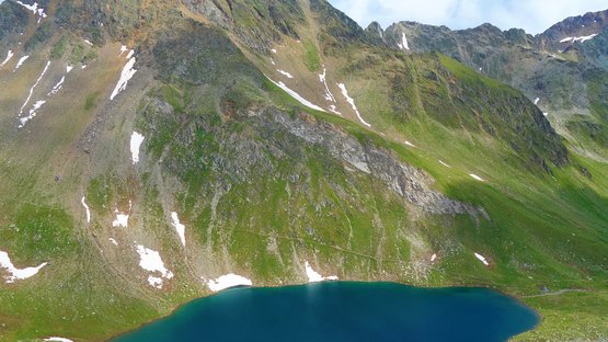 Lago Ponte di Ghiaccio, bellezza alpina Lago alpino con neve sulle pendici verdi sotto cielo nuvoloso