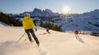 Skihotels in Südtirol - Pistenglück und Winterspaß Vier Skifahrer fahren bei sonnigem Wetter auf verschneiter Bergpiste