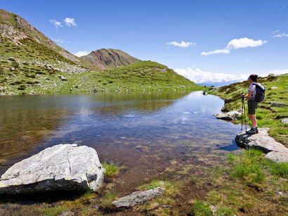 Von Matsch aus auf die Weißkugel Wanderer steht am Bergsee mit grünem Gras und blauem Himmel