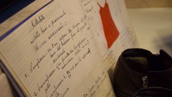 Museo delle donne di Merano Appunti scritti a mano e disegno rosso di un vestito su un quaderno a quadretti