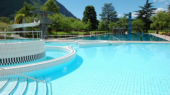 Bozner Lido – Treffpunkt für Jung und Alt Leeres Freibad mit Rutschen, Sprungtürmen und Bergen im Hintergrund