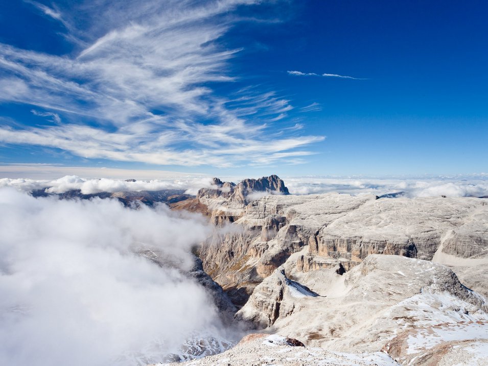 Passo Pordoi Montagne rocciose con cielo azzurro e nuvole sotto le cime