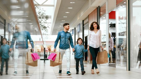 Maxi Mode Center in Südtirol Familie beim Einkaufen im Einkaufszentrum mit Tüten in der Hand