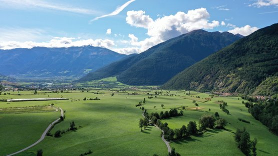 Hotel a Burgusio in Val Venosta Prati verdi e colline sotto un cielo blu con montagne sullo sfondo