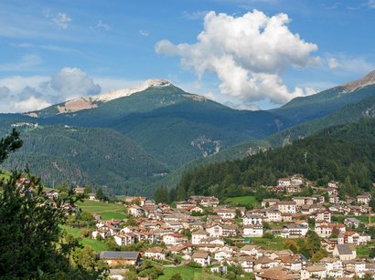 Il Salto, escursione con vista panoramica Vista di un villaggio alpino con montagne e colline boschive sotto un cielo limpido
