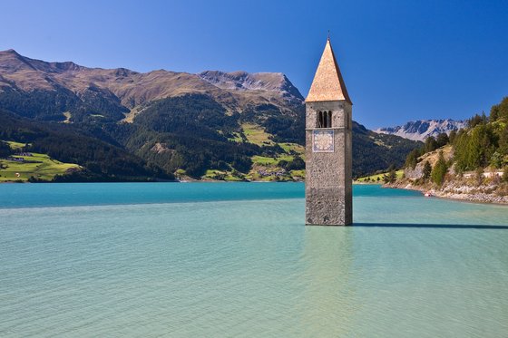 Reschensee: Naturparadies in Südtirol Kirchturm ragt aus einem See mit Bergen im Hintergrund