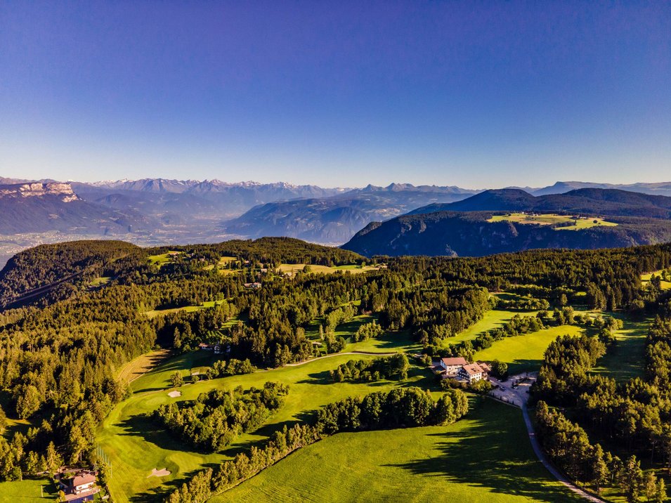 Golfclub Petersberg Luftaufnahme eines grünen Golfplatzes in den Bergen unter klarem blauem Himmel