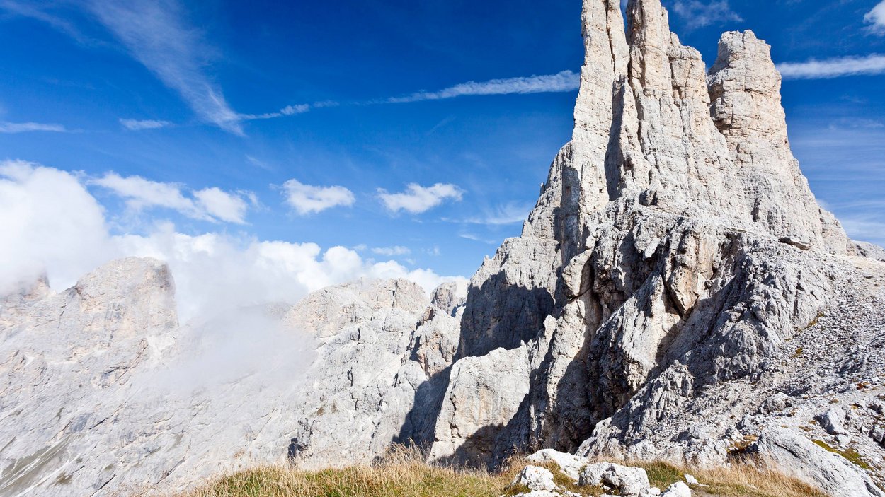 Wanderung in den Dolomiten Felsformation in den Bergen bei klarem Himmel und etwas Gras im Vordergrund