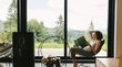 Appartamenti vacanze in Alto Adige Donna legge rilassata davanti a una grande finestra con vista su bosco e montagne