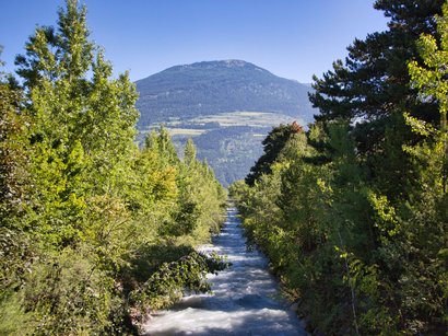 Hotels in Burgstall: der perfekte Ort für Genießer Fluss fließt durch grüne Bäume mit Berg im Hintergrund bei klarem Himmel