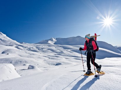 Winterwanderung Ranui – Zanseralm – Glatschalm – Dusler - Ranui Frau mit Schneeschuhen wandert auf schneebedecktem Berg bei sonnigem Himmel