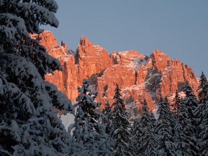 18 SEXTEN - Rundloipe Fischleintal Schneebedeckte Tannen vor roten Felsklippen im Sonnenuntergang