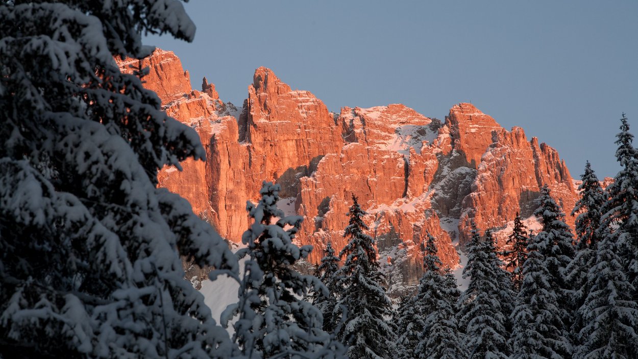 Obereggen – una chicca per i fondisti Abeti innevati davanti a scogliere rosse al tramonto