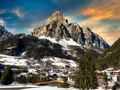 The mountain beast for golfers Dorf mit verschneiten Häusern vor einem großen Berg bei Sonnenuntergang