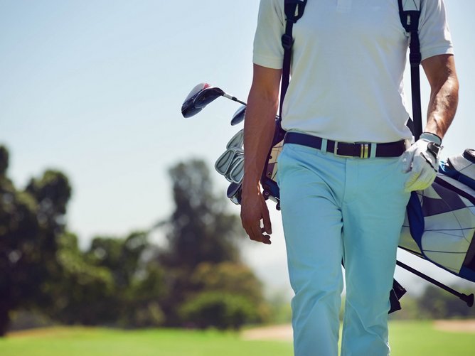 Golfen in Südtirol Golfspieler mit Golftasche und Schlägern auf dem Golfplatz
