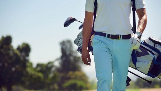Golfen in Südtirol Golfspieler mit Golftasche und Schlägern auf dem Golfplatz