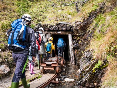 Das Naturparkhaus im Ahrntal Gruppe von Menschen mit Helmen betritt Stolleneingang in den Bergen