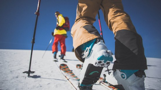 Rotbachlspitze (2.898 m) - Im Angesicht von Hochferner und Schrammacher Skifahrer in Skischuhen laufen mit Stöcken auf verschneitem Hang