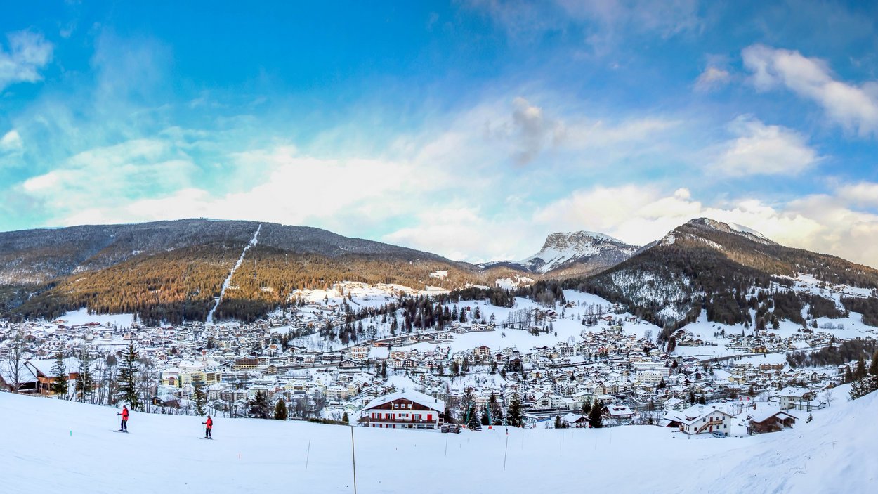 Sfrecciare con lo slittino in Val Gardena Panorama invernale di una città innevata con montagne e sciatori in primo piano