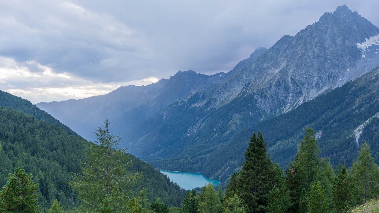 Parco naturale Ries-Aurina Paesaggio montano con foreste di conifere e un lago in valle sotto cielo nuvoloso
