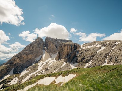 Die Natur in und um Südtirol Berglandschaft mit Felsen, Schneeflecken und grünem Gras unter blauem Himmel