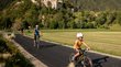 Schloss Reifenstein bei Sterzing Kind und Erwachsene fahren mit Helm auf Fahrrädern auf einem Weg mit Burg im Hintergrund
