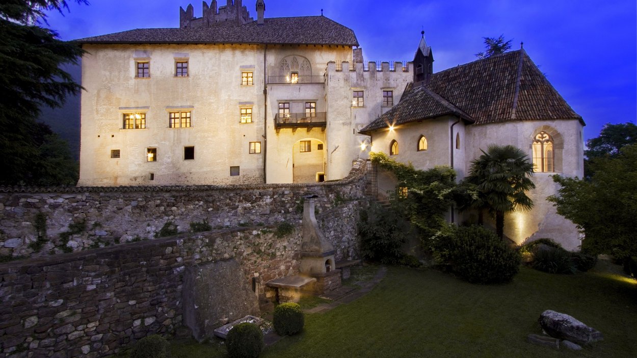 Castel Freudenstein ad Appiano Castello storico illuminato al tramonto con muro di pietra e giardino