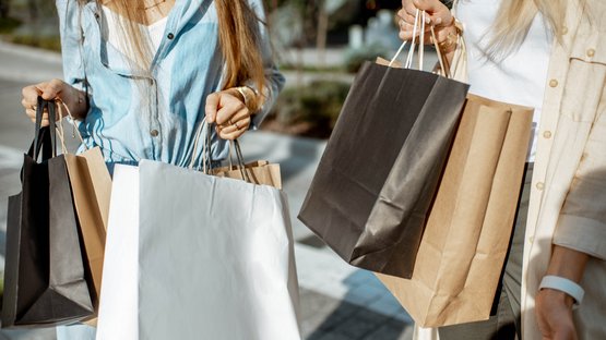 Outlet Center Brenner Due donne che portano buste della spesa a mano su un marciapiede