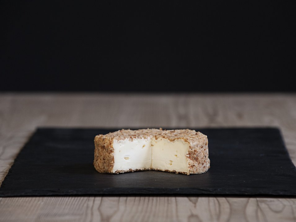 Capriz Feinkäserei Formaggio molle tagliato a metà con crosta marrone su piatto nero