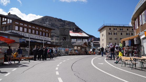 Die Stilfserjochstraße lässt jedes Bikerherz höherschlagen Bergdorf mit Hotels, Marktständen und Menschen bei klarem Himmel