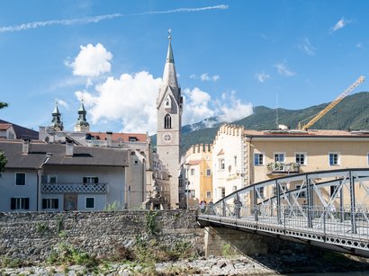 Hotel a Naz-Sciaves Edifici storici e un ponte in una città alpina sotto un cielo sereno