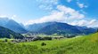 Der Falzaregopass Grünes Tal mit Dorf vor bewaldeten Bergen unter blauem Himmel