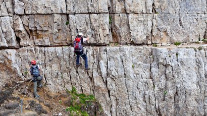 Lungo la Val Pusteria Due scalatori con casco e attrezzatura su una parete rocciosa ripida