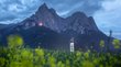 Fuochi del Sacro Cuore in Alto Adige Campo di fiori davanti a montagna e torre campanaria con cielo nuvoloso alla sera