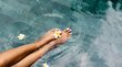 Luxushotels in Südtirol - Eleganz & Service Füße im Wasser mit weißen Blumen an einem Pool