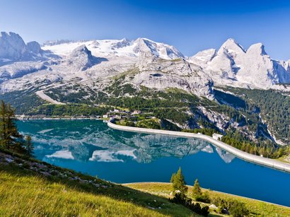 Unterwegs in den Dolomiten Bergsee mit Staumauer und schneebedeckten Bergen im Hintergrund