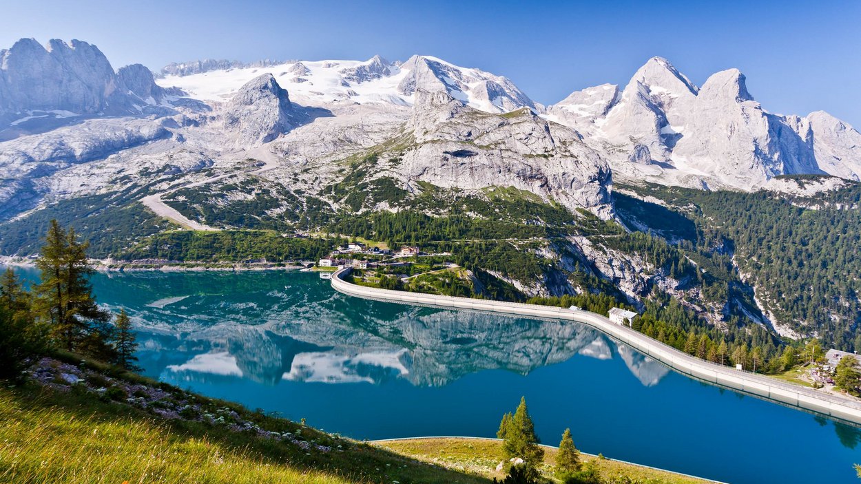 Der Fedaiapass Bergsee mit Staumauer und schneebedeckten Bergen im Hintergrund
