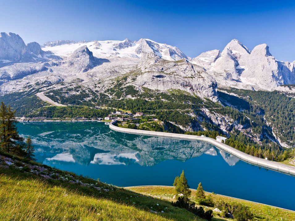 Der Fedaiapass Bergsee mit Staumauer und schneebedeckten Bergen im Hintergrund