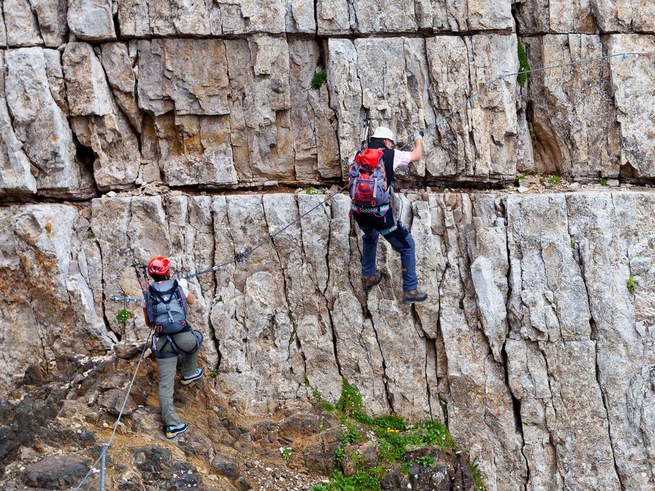 Der Pößnecker-Klettersteig in den Dolomiten Zwei Personen klettern mit Kletterausrüstung an einer Felswand