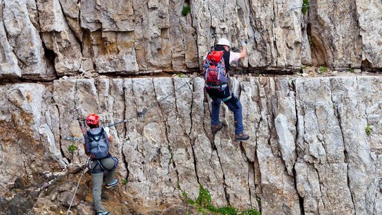 Der Pößnecker-Klettersteig in den Dolomiten Zwei Personen klettern mit Kletterausrüstung an einer Felswand