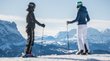 Hotels am Kronplatz im Pustertal Zwei Skifahrer blicken auf verschneite Berglandschaft bei klarem Himmel