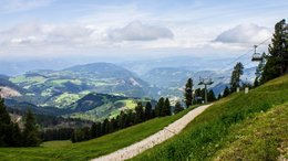 Hotels am Rosengarten und Latemar Berglandschaft mit Wanderweg, grüne Wiesen und Sessellift unter blauem Himmel