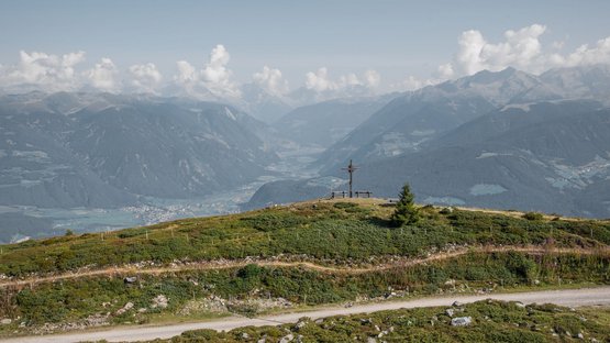 Hotel a Plan de Corones Cima della montagna con croce, panchine e vista sulla valle con cielo limpido