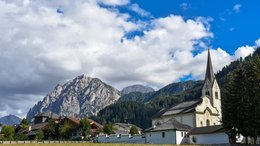 Hotel sulle Dolomiti Chiesa e case con montagne e cielo nuvoloso sullo sfondo