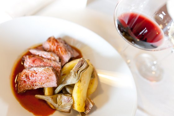 Hotel gourmet in Alto Adige Carne rosa con carciofi e patate, accompagnata da un bicchiere di vino rosso